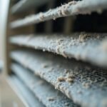 Close-up of the dust-clogged filter and louvres of a wall-mounted air conditioner indoor unit